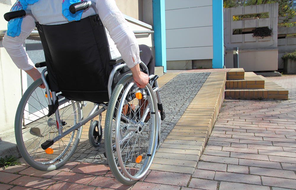 Person in a wheelchair using a ramp to enter a building